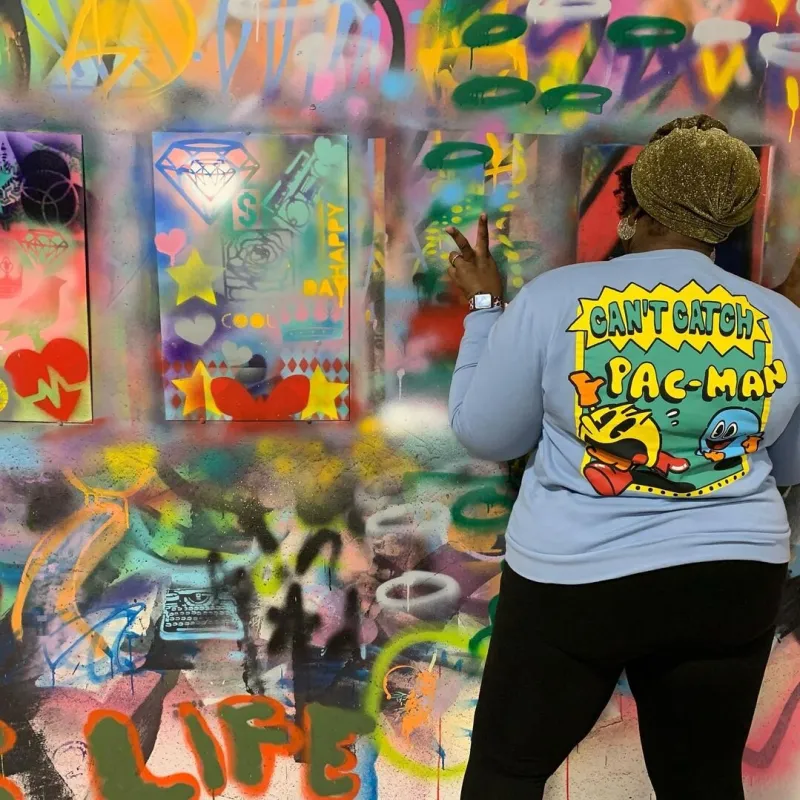 a man standing next to a graffiti covered wall